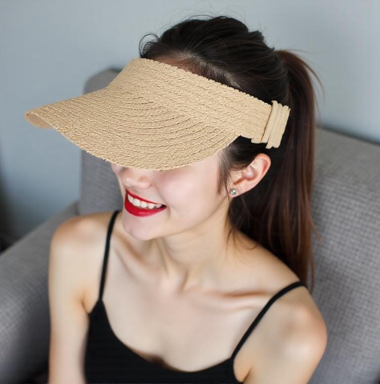 Woman smiling and wearing a straw sun hat visor with a wide brim. Lightweight and stylish summer cap for beach, outdoor UV protection, vacation, honeymoon, garden, or as a thoughtful gift for her mom.