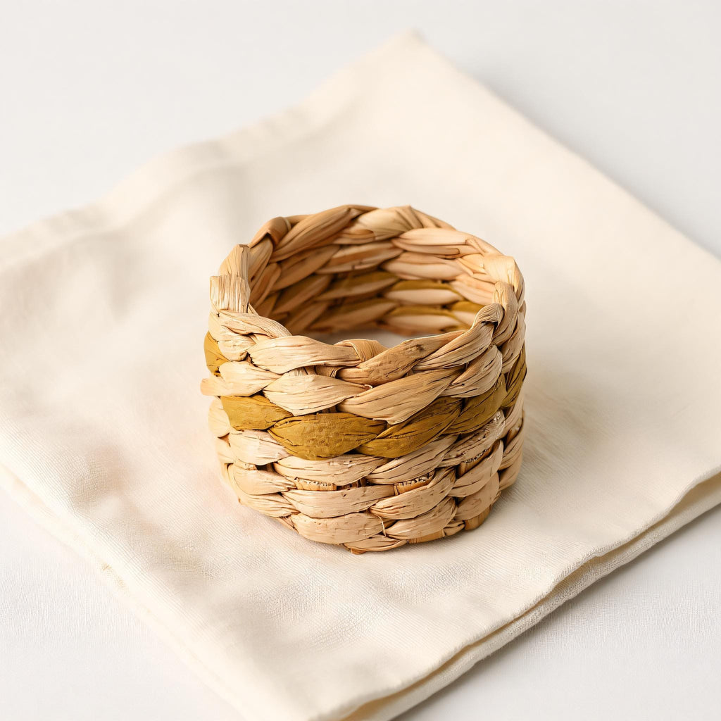 A woven basket made of natural materials, such as grass or reeds, is placed on a white cloth napkin.