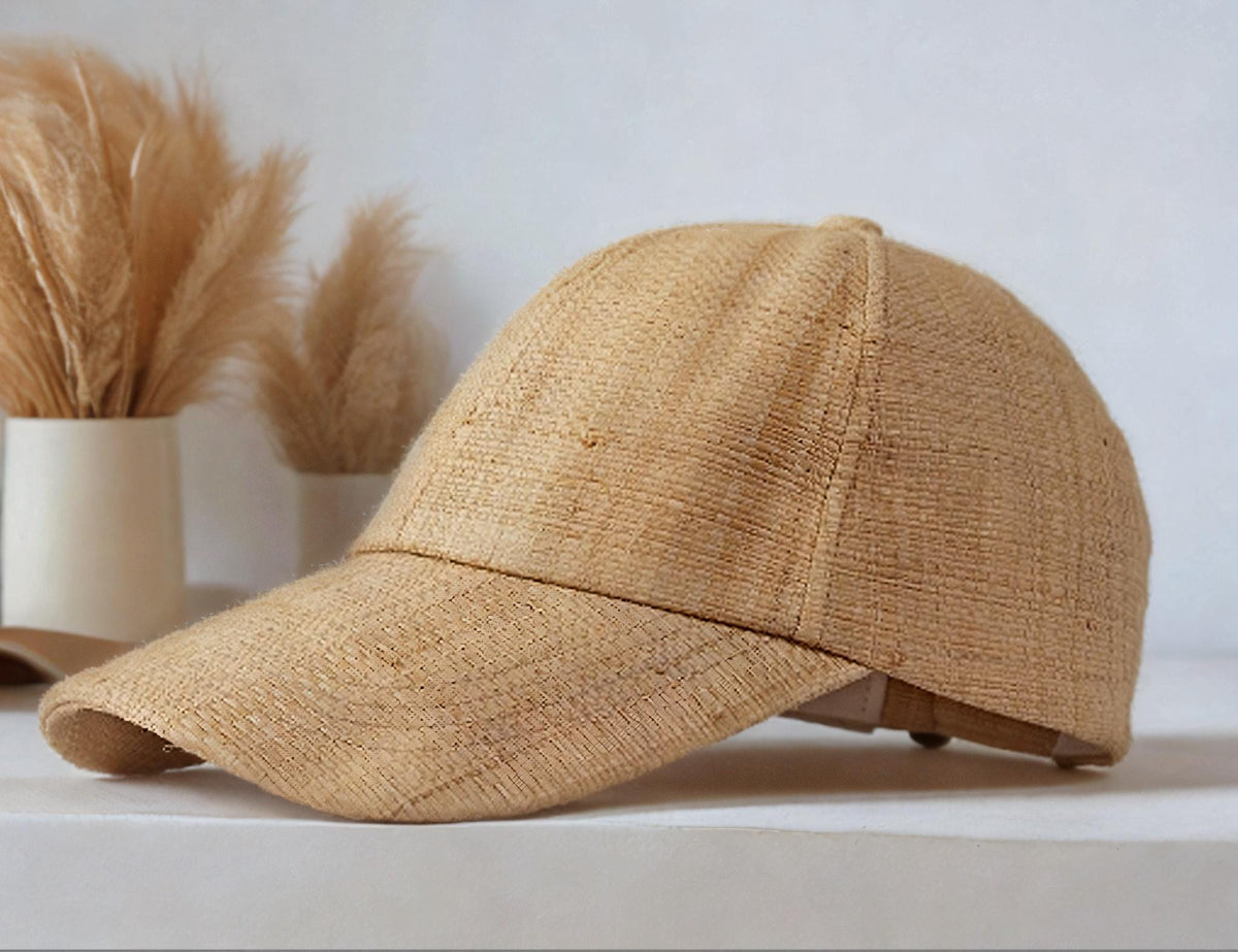 Natural straw sun hat baseball cap with curved brim, displayed on a white surface beside dried plants. Lightweight and stylish summer hat for beach, outdoor UV protection, vacation, garden, honeymoon, or as a gift for her mom.