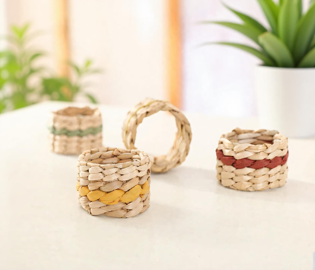 three woven baskets or containers on a white surface, with a potted plant in the background.