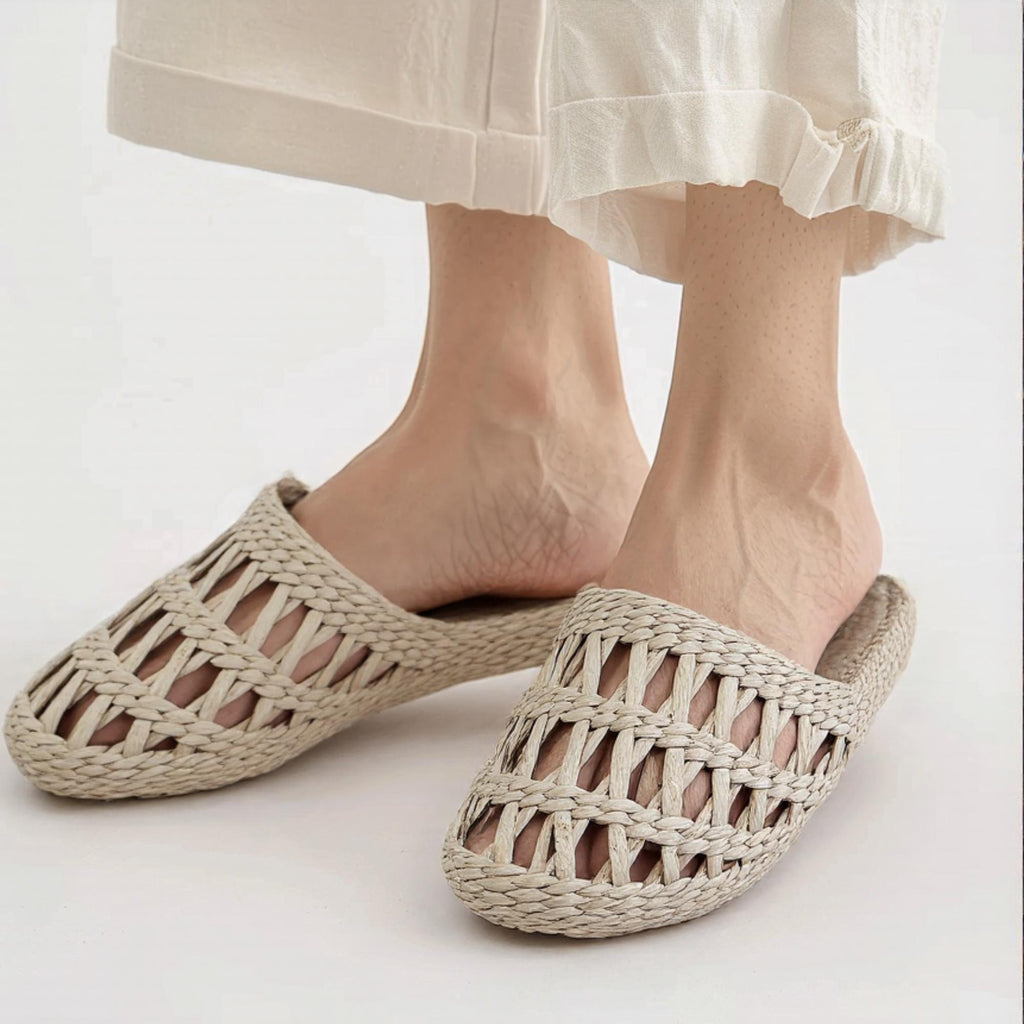 Woman wearing handmade straw slippers with closed toe and open weave pattern, paired with light-colored skirt. Natural beige color, lightweight and breathable, ideal for summer house shoes.