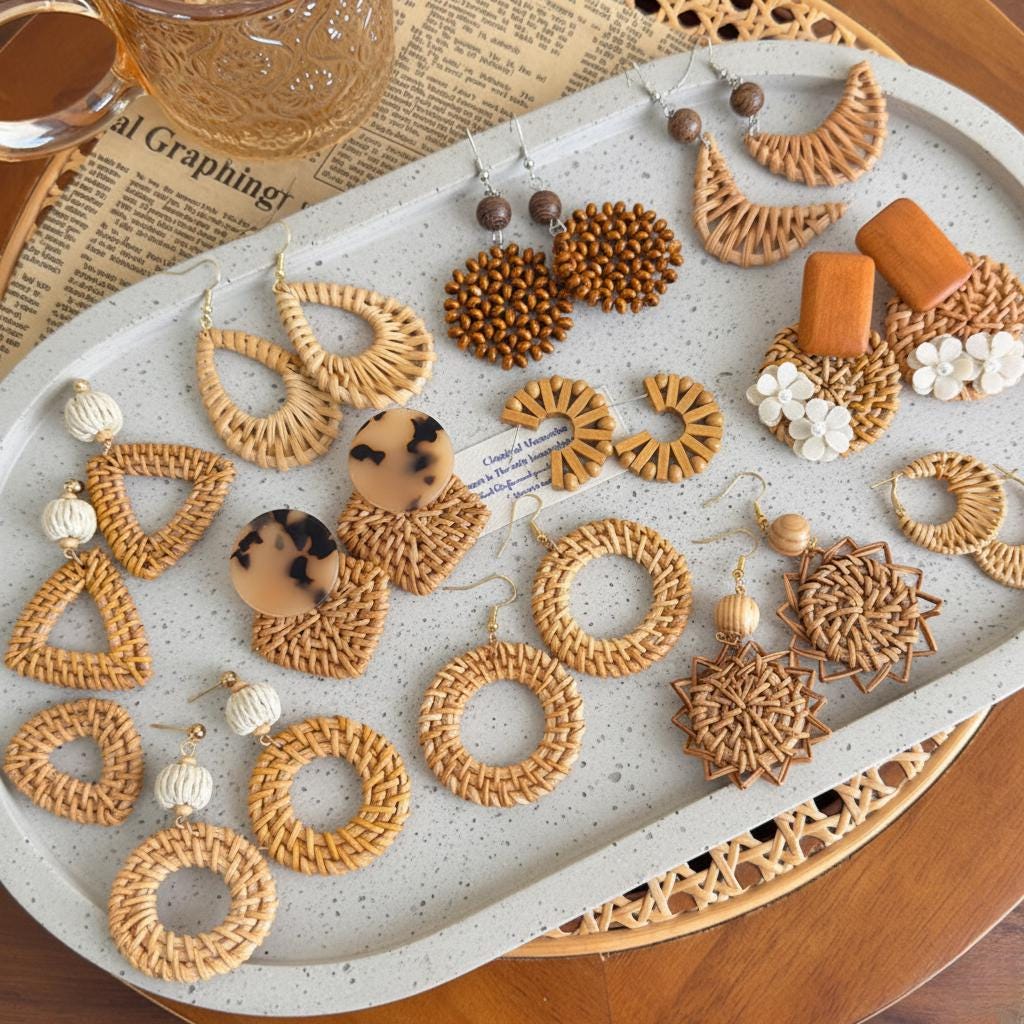 a variety of earrings made from natural materials, such as woven straw and beads, arranged on a tray.