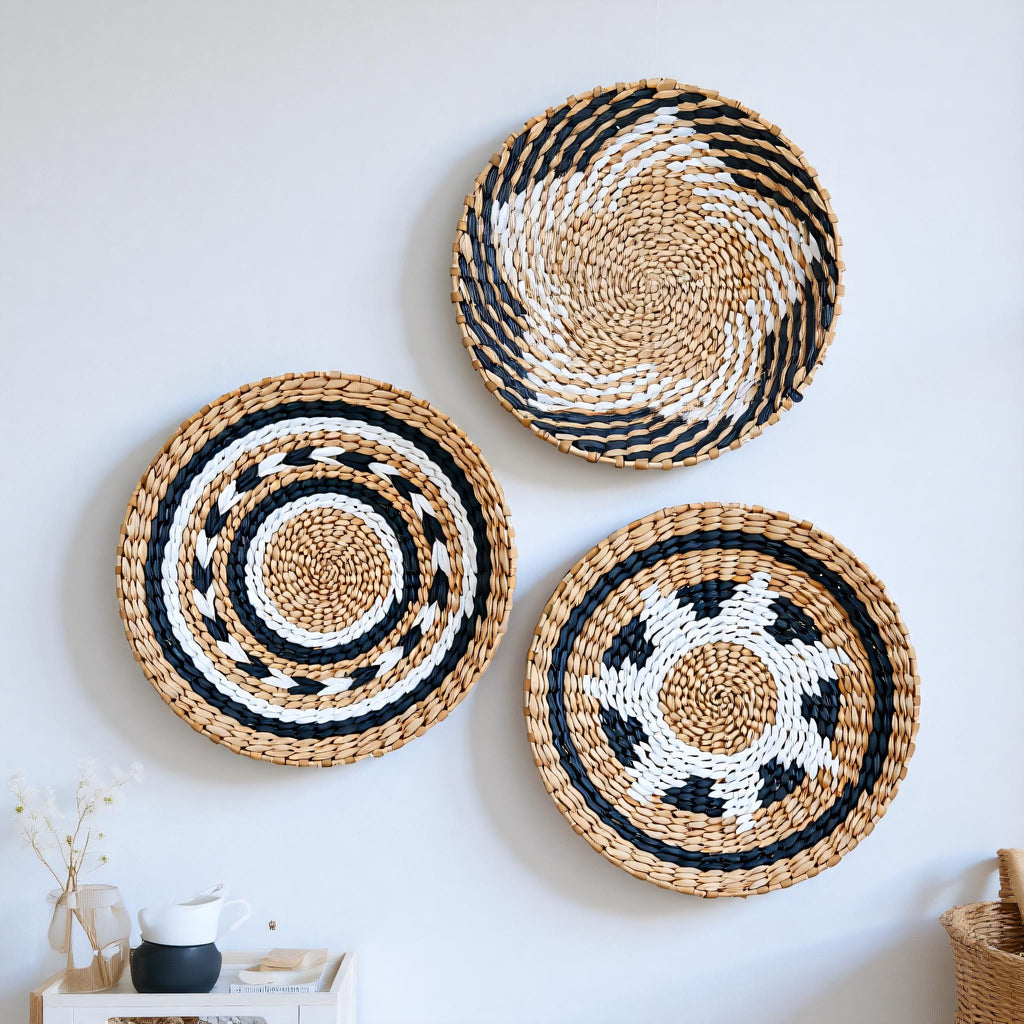 three woven baskets hanging on a white wall, each with a unique design and pattern.