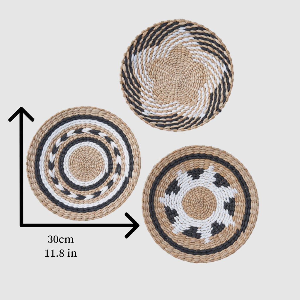 three woven baskets or plates with different patterns and designs, including a circular pattern, a spiral pattern, and a plate with a geometric design.