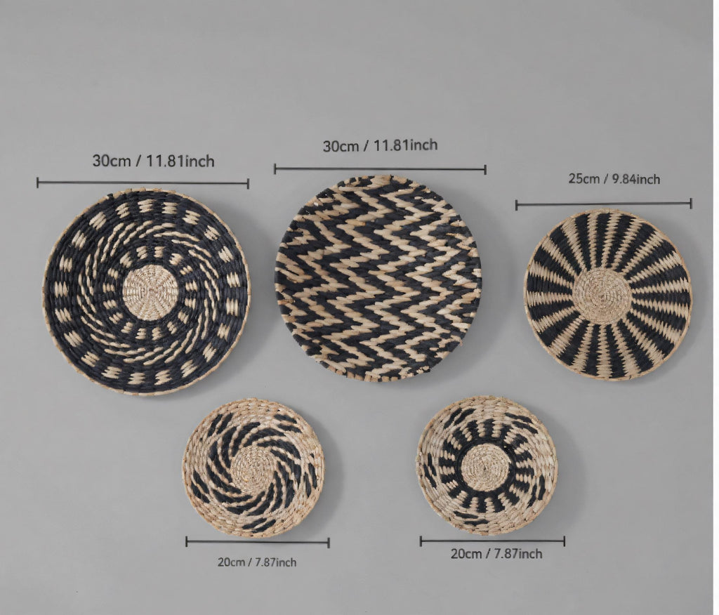 a collection of five woven baskets or plates, each with a unique design and size, arranged side by side against a grey background.