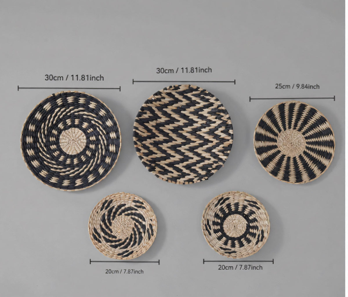 a collection of five woven baskets or plates, each with a unique design and size, arranged side by side against a grey background.