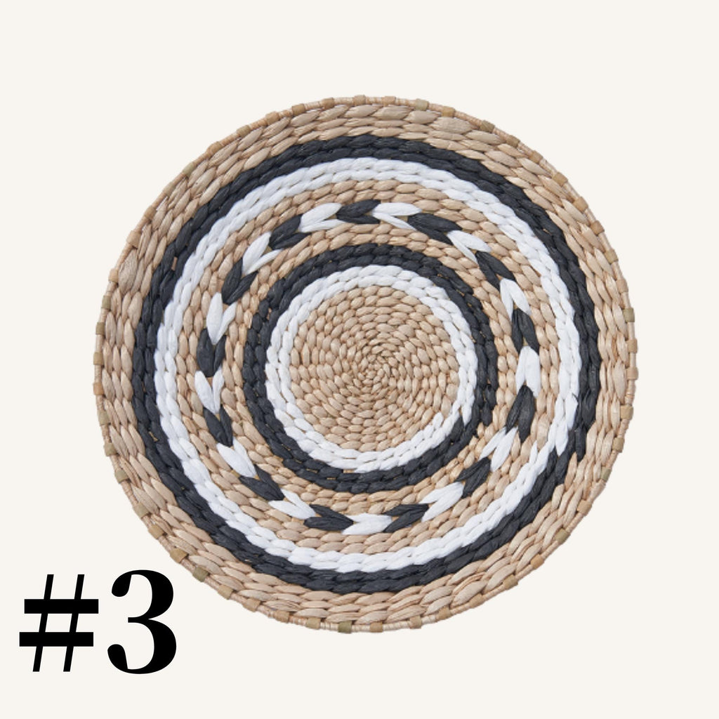 A woven placemat with a circular pattern of alternating black and white stripes.