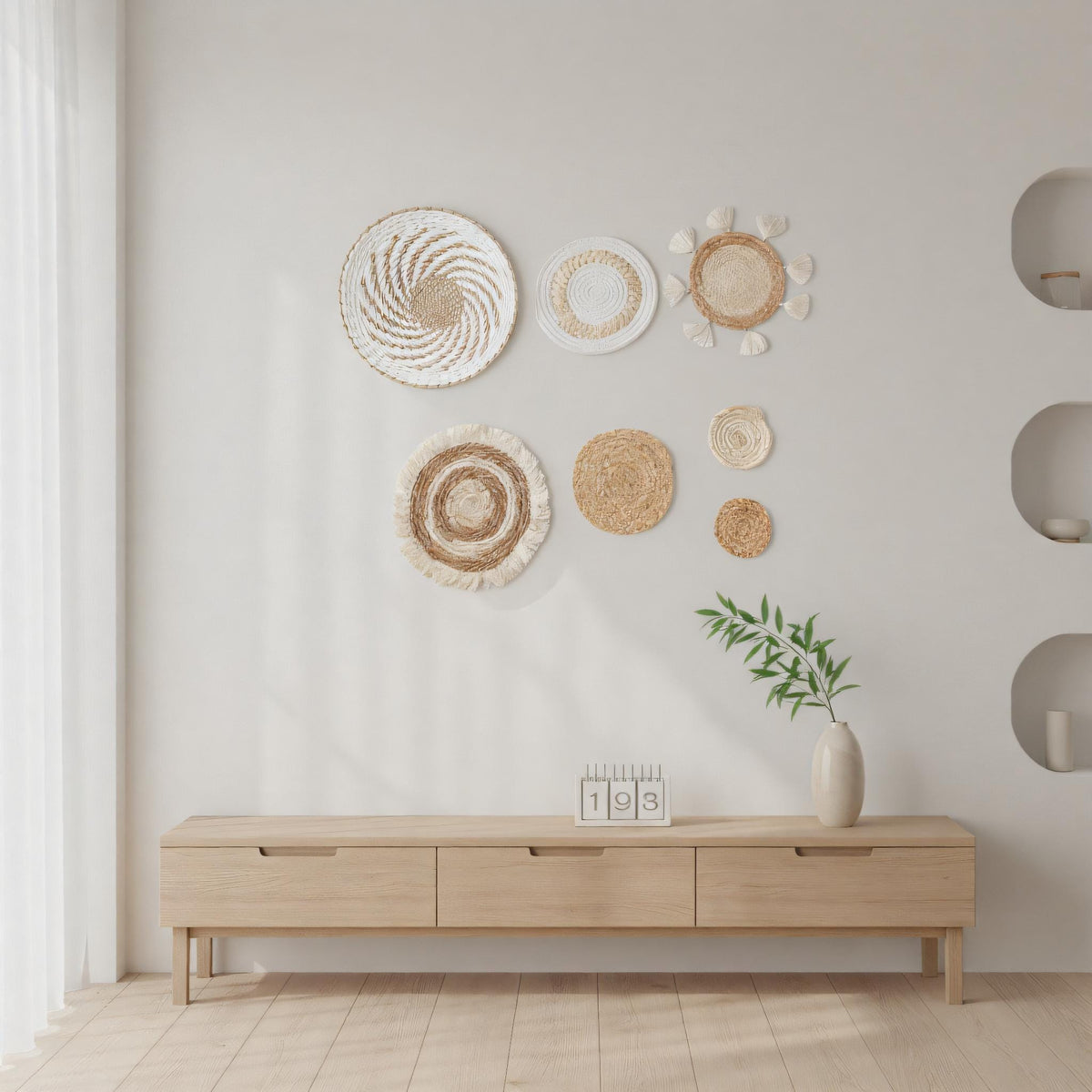A minimalist living room with a wooden entertainment center, a vase with greenery, and various decorative items on the wall.