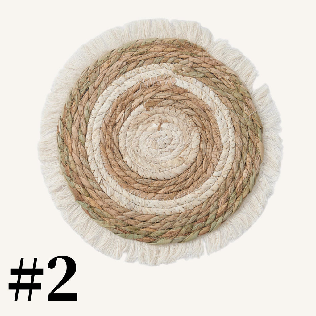 a round, woven mat with a fringed edge, placed against a white background.
