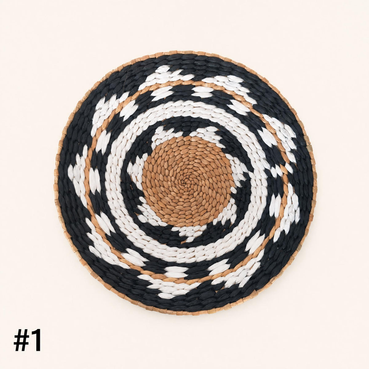 A woven mat with a circular pattern of black, white, and brown colors.