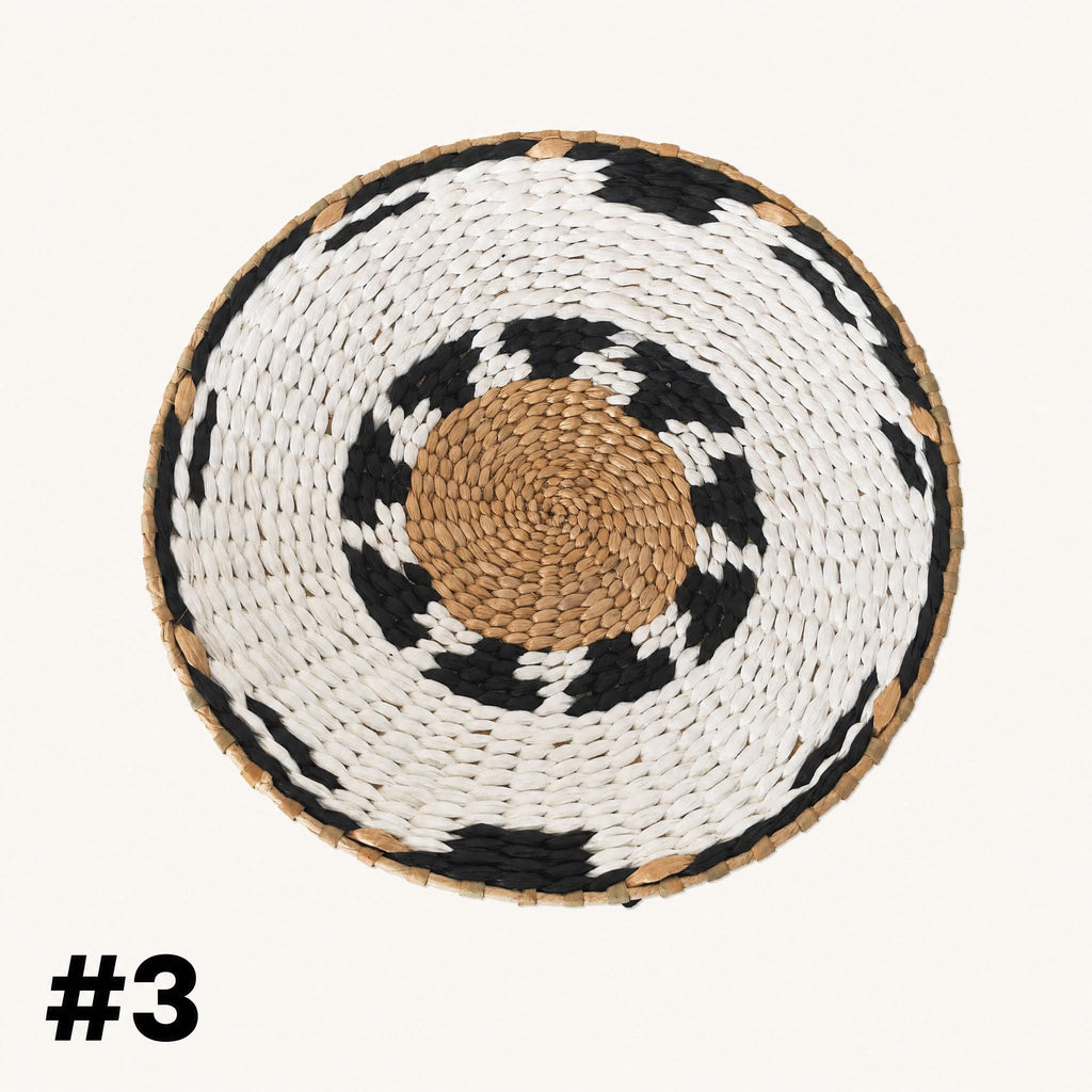 A woven basket with a circular pattern of white and black colors, featuring a central brown circle.