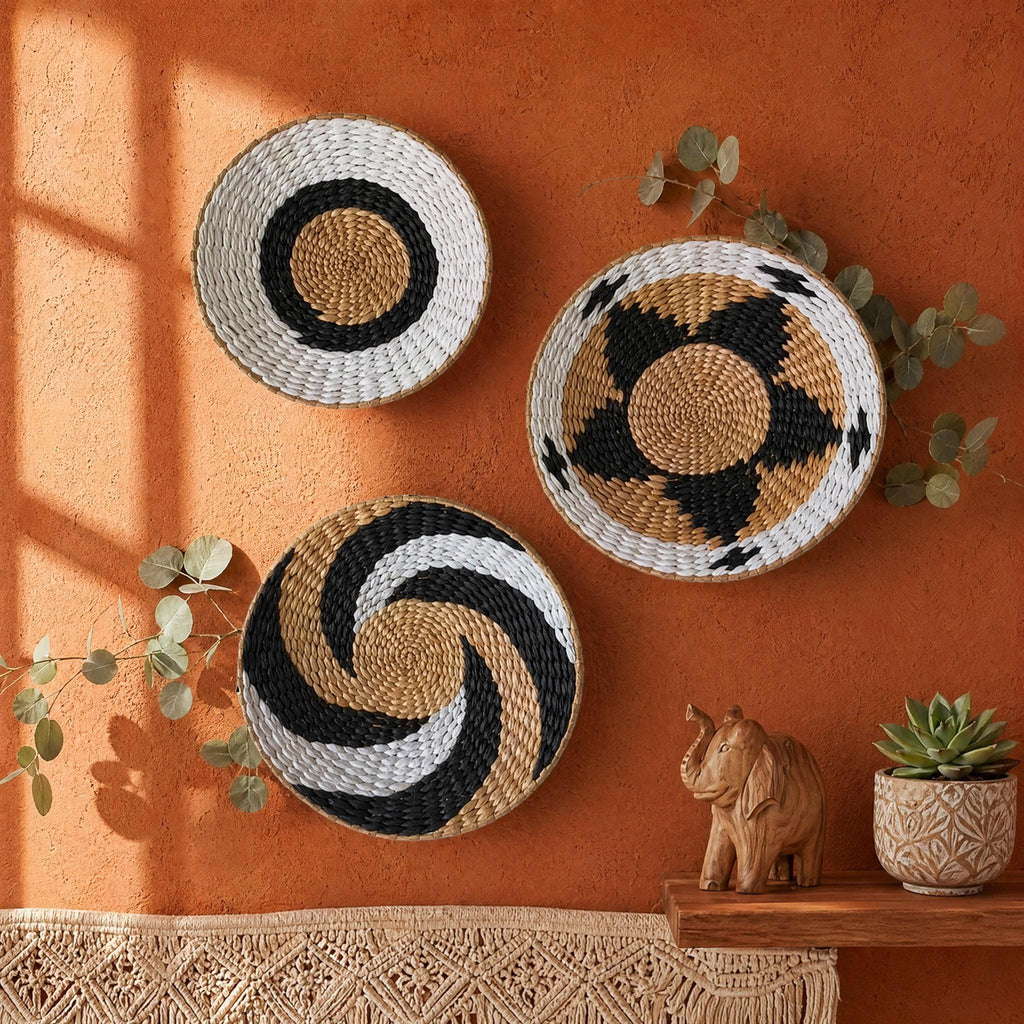 three woven baskets with different patterns, including a circular pattern, a spiral pattern, and a star pattern, hanging on a wall. The baskets are placed next to a wooden elephant figurine and a potted succulent plant, creating a decorative and harmonious display.