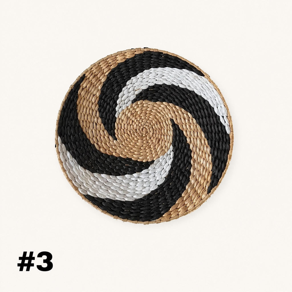 a decorative woven dish with a spiral pattern in black, white, and gold colors.