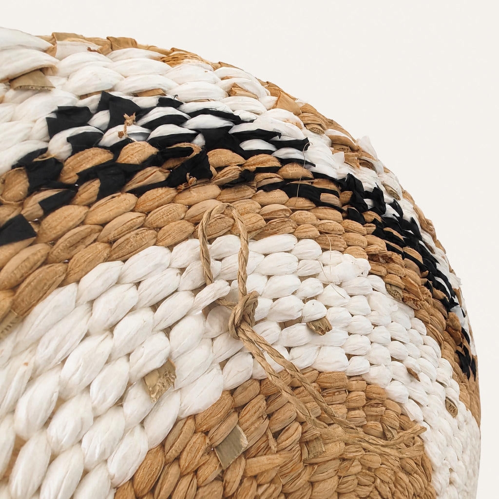a close-up view of a woven basket or textile with a distinctive pattern of white, brown, and black colors.