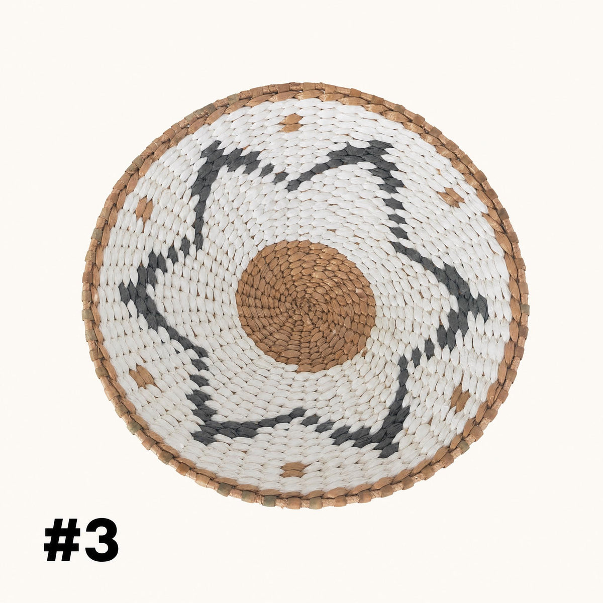 A woven basket with a circular design in the center, featuring a mix of white, brown, and black colors.