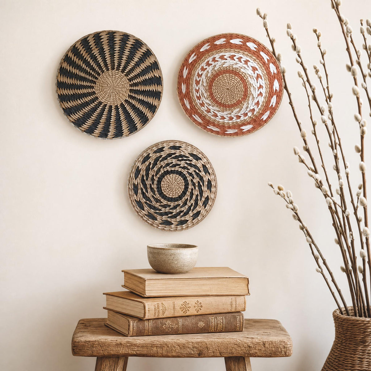 a wooden stool with a stack of books on top, and two decorative woven baskets hanging on the wall above it.