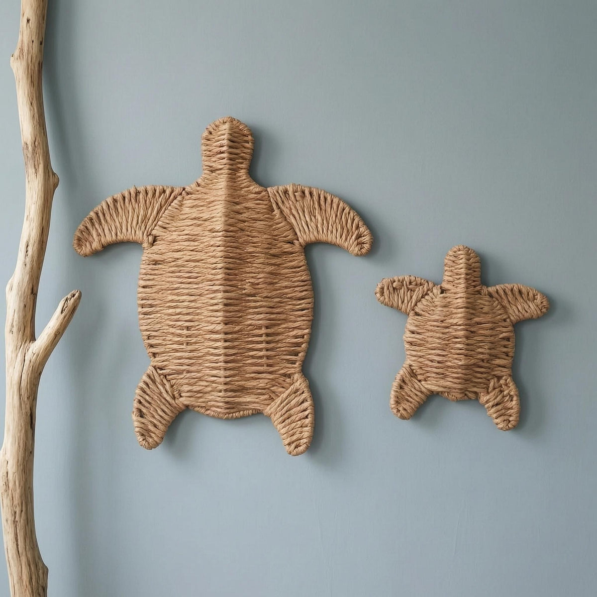two woven turtle-shaped wall decorations, one larger and one smaller, hanging on a light blue wall.