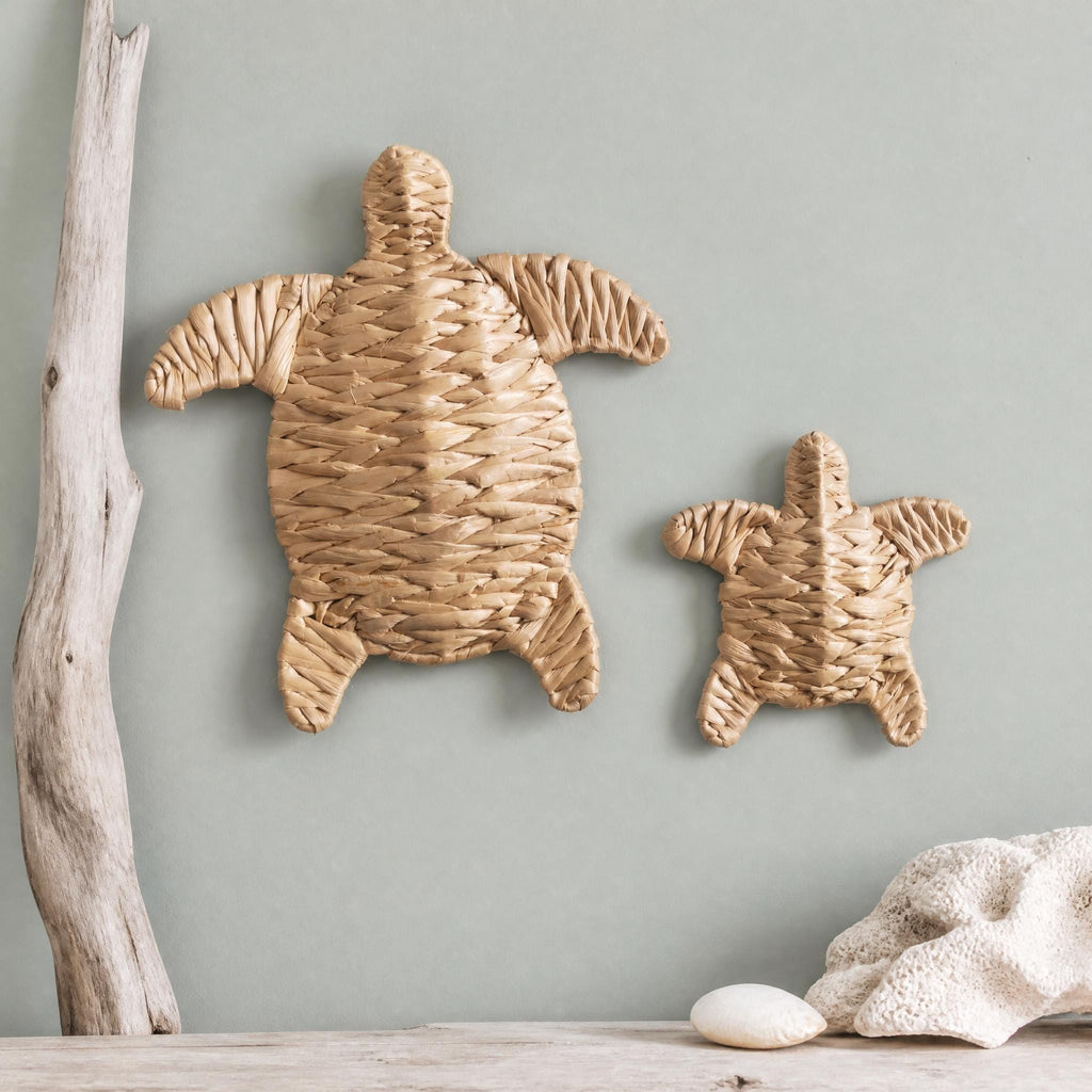 two turtle-shaped wall decorations made of woven materials, hanging on a light blue wall.