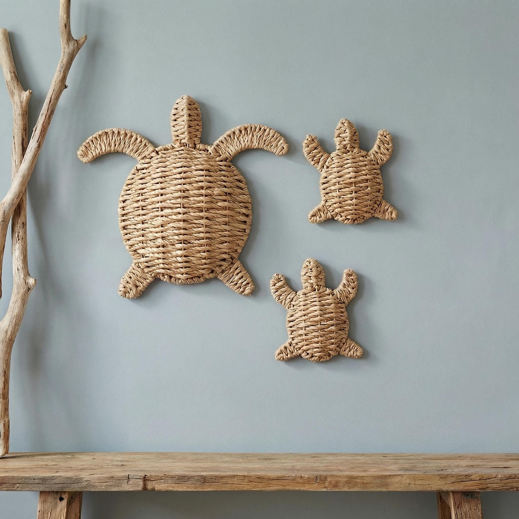 three woven turtle-shaped wall decorations, each with a unique design, mounted on a light blue wall above a wooden bench.