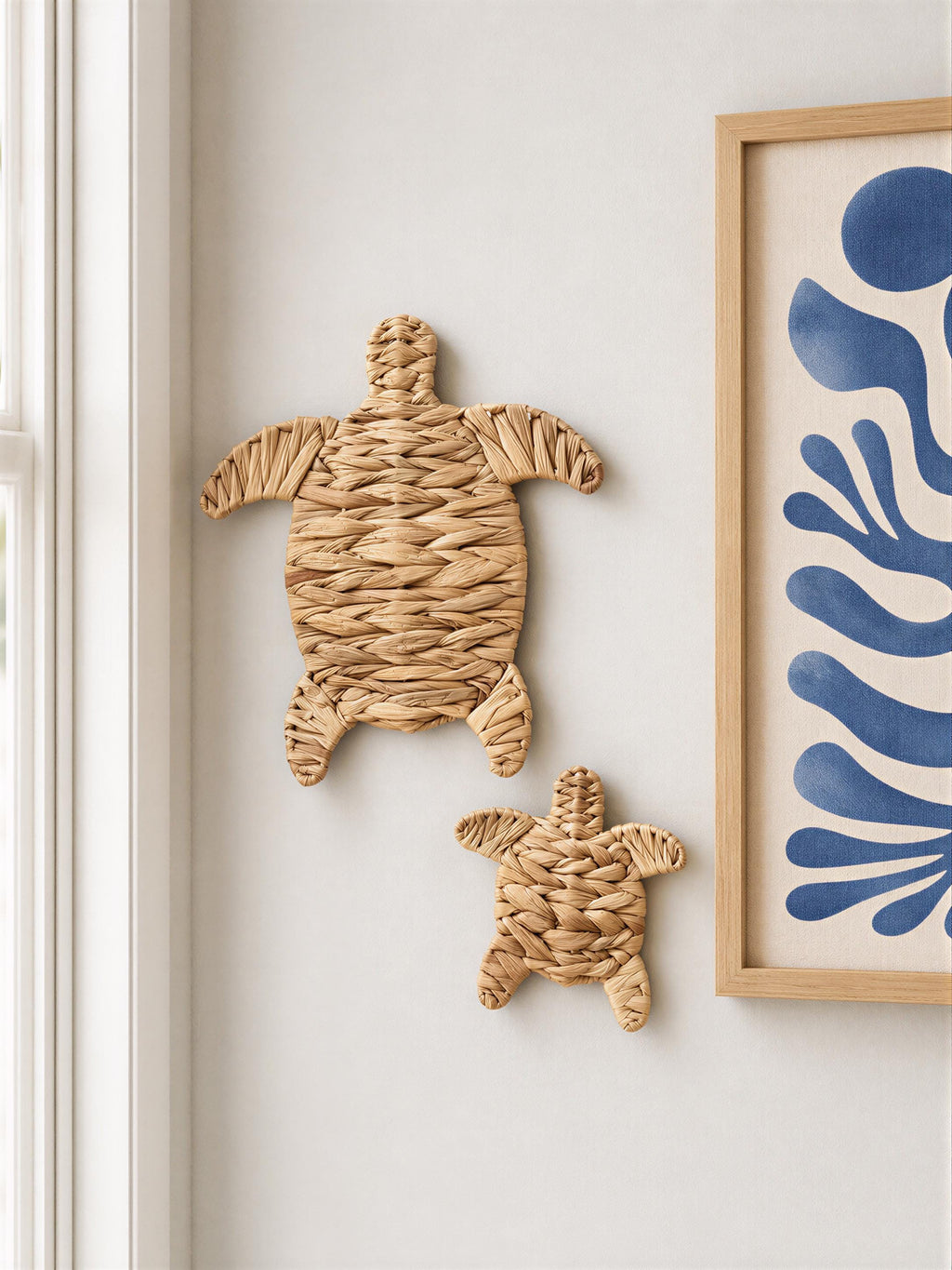 two woven turtle-shaped wall decorations hanging on a white wall.