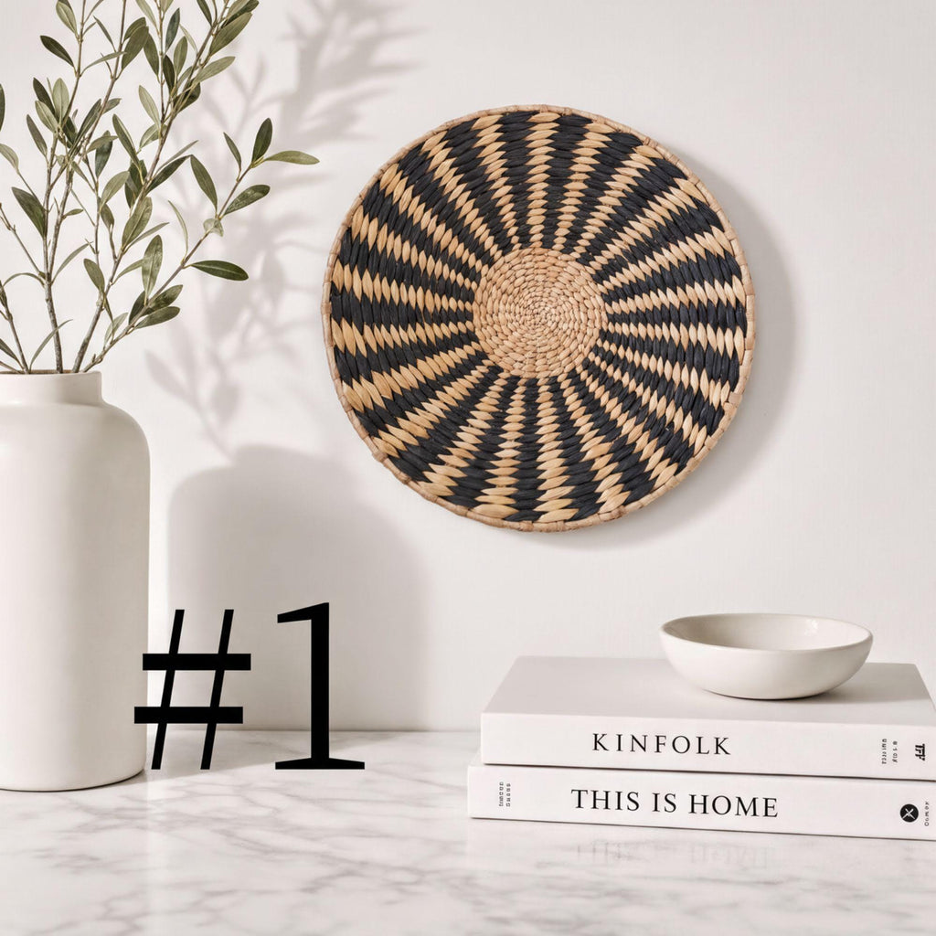 a white marble countertop with a white vase, a black and white woven basket, a stack of books, and a small bowl.