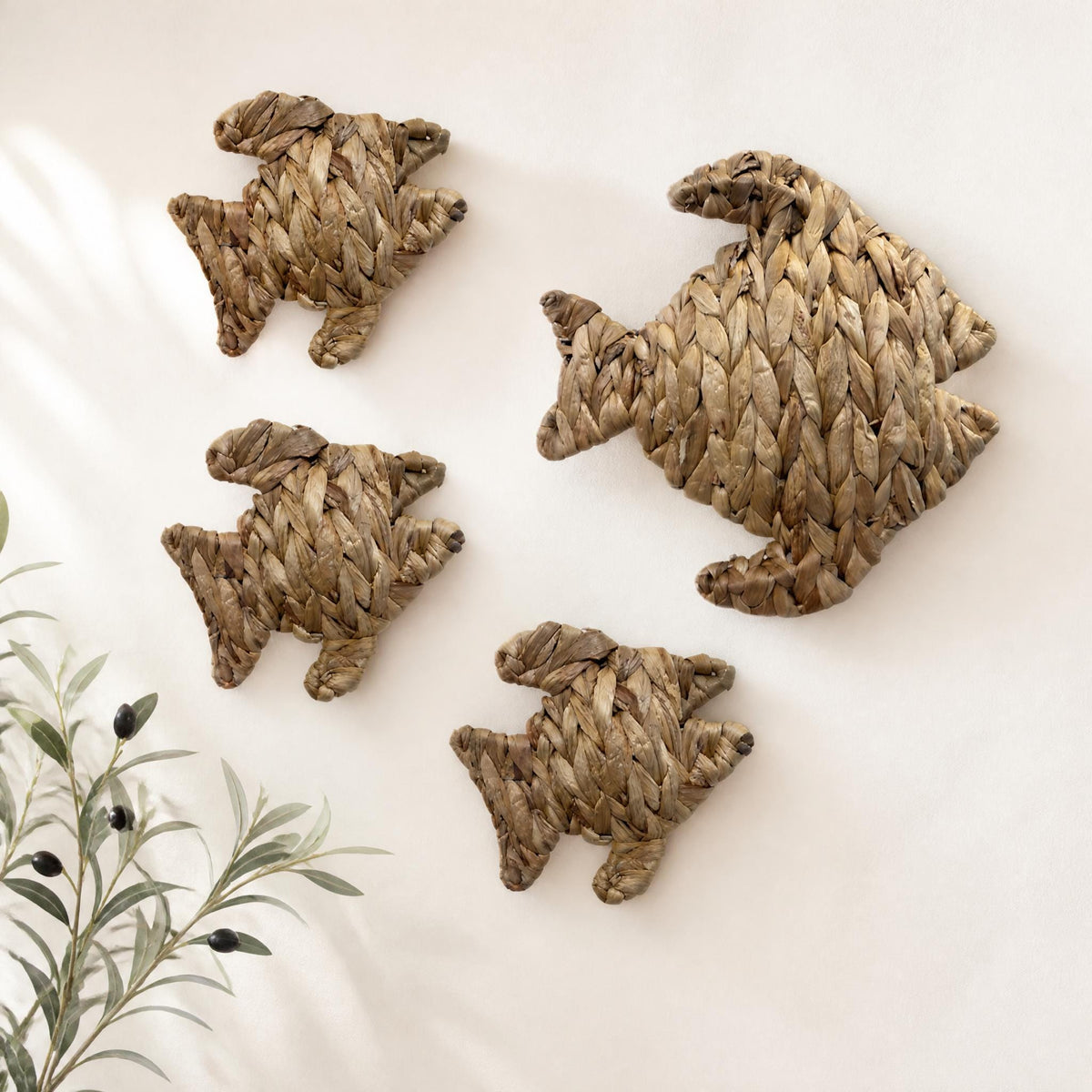 four woven fish-shaped wall decorations arranged on a white wall.