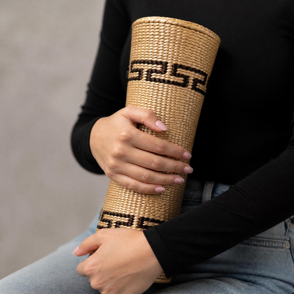 A person is holding a woven basket with a geometric pattern on it.