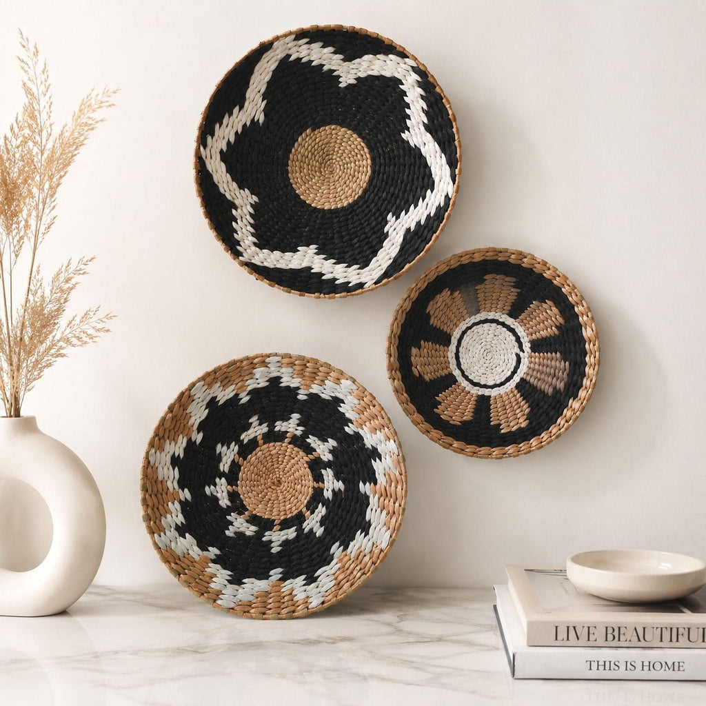 three decorative woven baskets hanging on a wall, placed on a marble countertop next to a white vase with dried flowers.