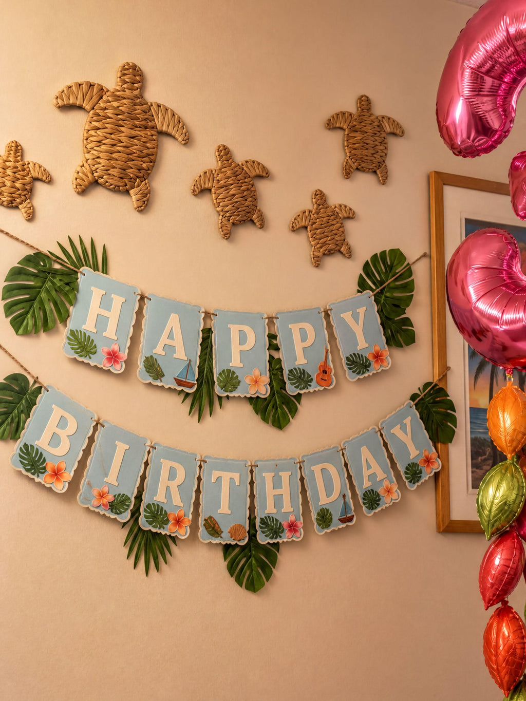 A birthday banner with the word "HAPPY" and "BIRTHDAY" written on it, along with decorative turtle and leaf-shaped objects. The banner is hanging on a wall, and there are colorful balloons and tropical leaves in the background.