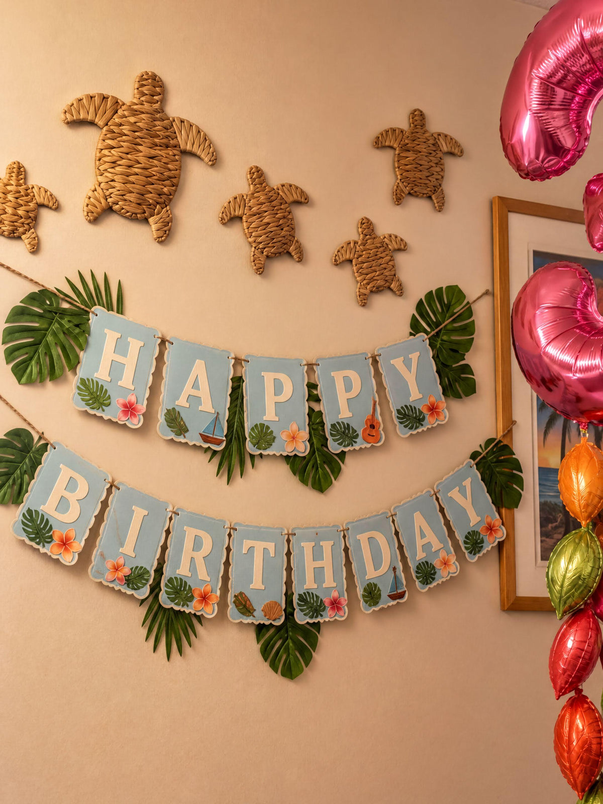 A birthday banner with the word "HAPPY" and "BIRTHDAY" written on it, along with decorative turtle and leaf-shaped objects. The banner is hanging on a wall, and there are colorful balloons and tropical leaves in the background.