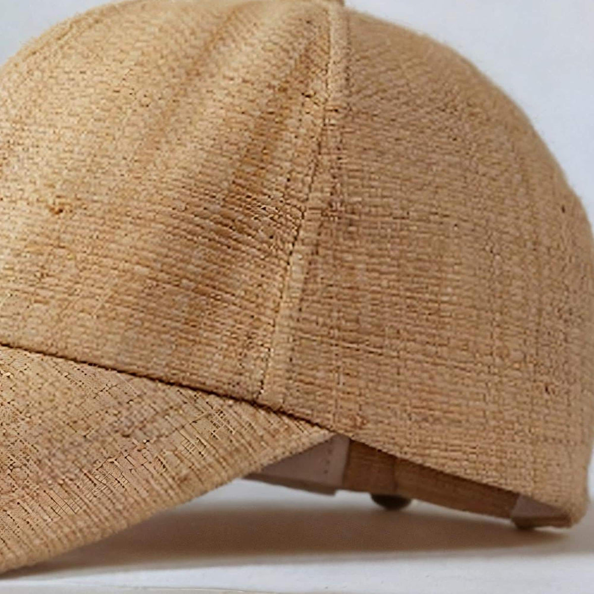 Close-up of the handwoven raffia straw texture and stitched panel seams of the baseball cap
