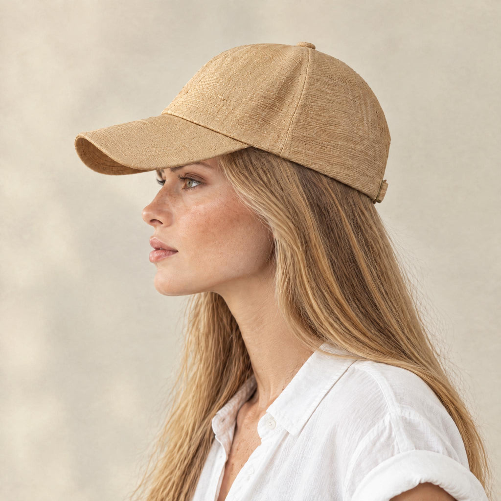 Woman wearing the handmade natural raffia straw baseball cap, side profile showing the curved brim
