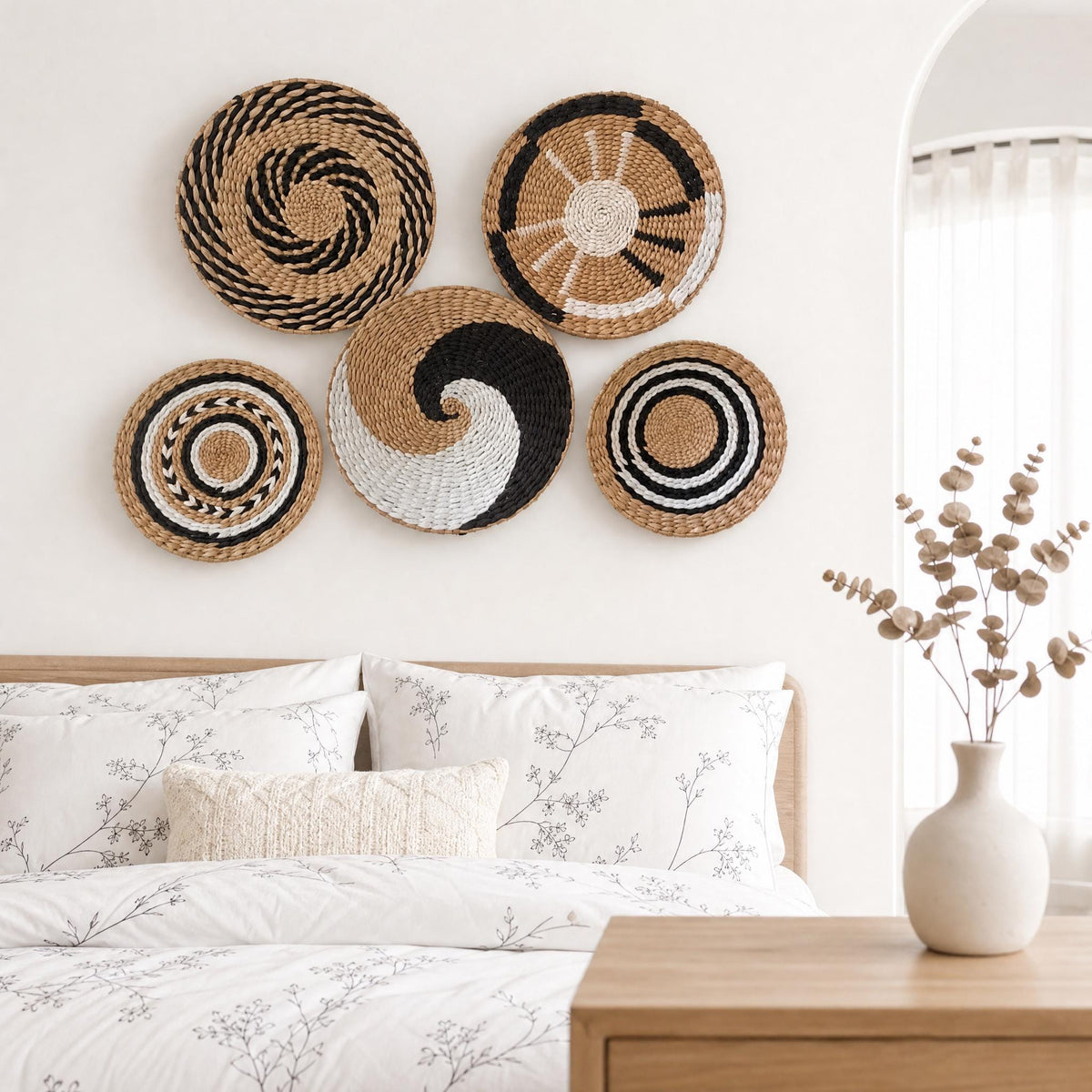 Five woven cattail wall baskets styled as boho bedroom wall decor above a bed