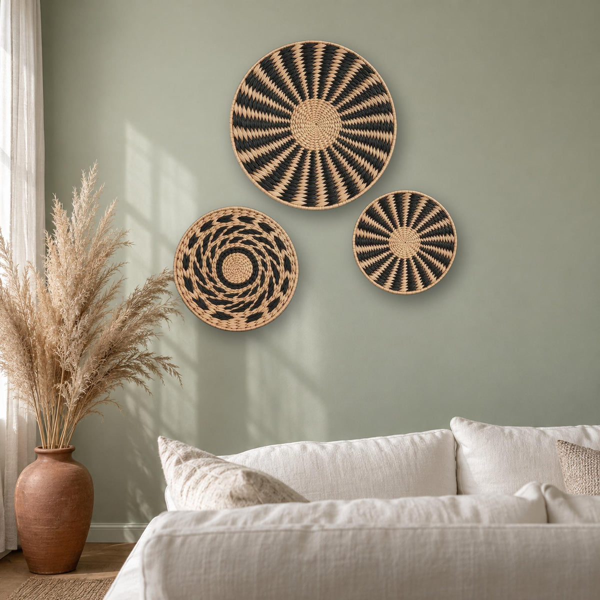 Three round woven cattail wall baskets as boho living room wall decor on a sage green wall with pampas grass